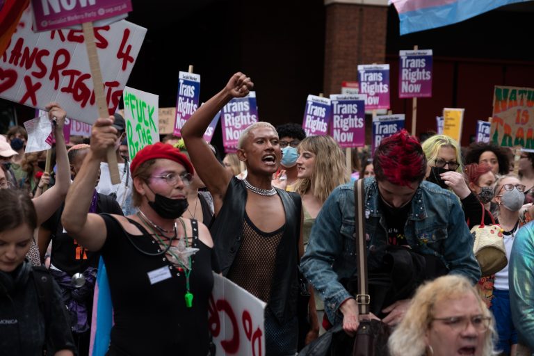 A group of activists protest outside in support of trans rights.