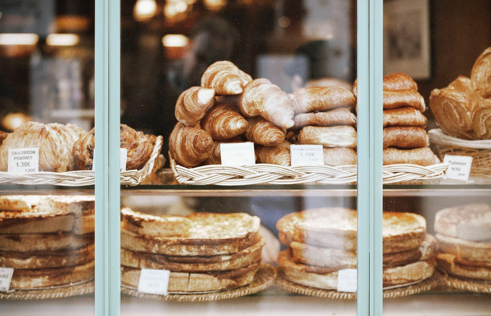 The window of a bakery shelf, which holds various trays of pastries